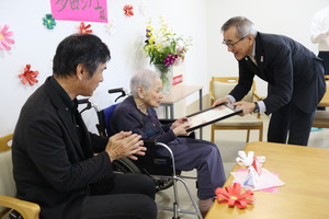 お祝いの言葉を多田さんに手渡す奥塚市長