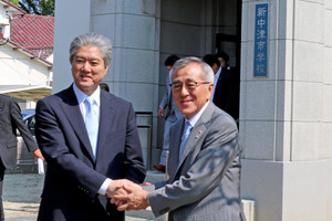 新中津市学校前で握手する長谷山塾長と奥塚市長