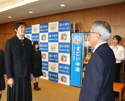 生徒からの出場報告を受ける奥塚市長（写真右）
