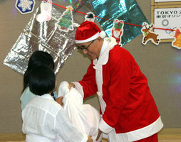 聖ヨゼフ寮で子どもたちにプレゼントを手渡す奥塚市長