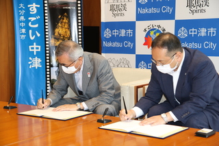 協定書に署名する奥塚市長（写真左）と井上代表取締役社長
