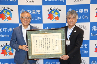 記念に写真を撮る城戸崎さんと奥塚市長（左）