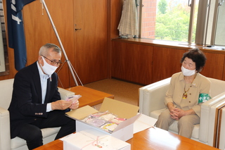 手作りマスクを手に取る奥塚市長（写真左）