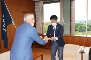 菊池会長から助成金を受け取る奥塚市長（写真左）
