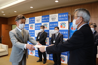 任命書を手渡す奥塚市長（市長は写真右）