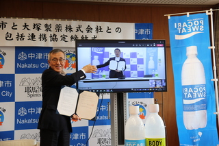 画面越しに握手する奥塚市長（写真左）