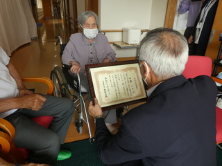 お祝い状を渡す奥塚市長（写真右）