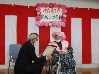 お祝い状を渡す奥塚市長（写真左）