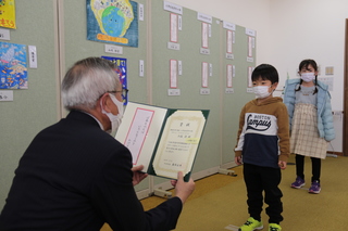 表彰状を読み上げる奥塚市長（写真手前）